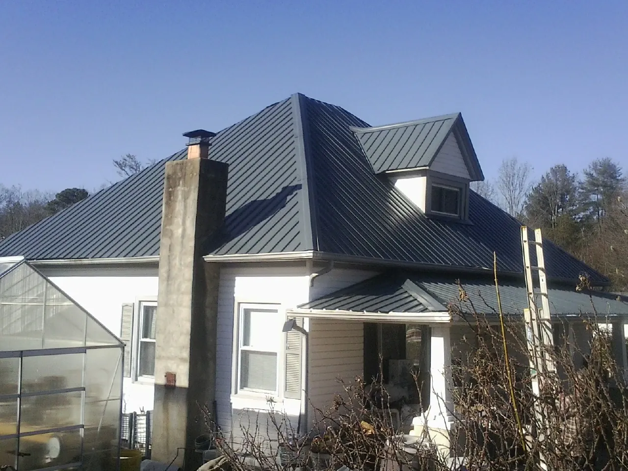 Dark blue standing seam metal roof on a white farmhouse with dormer — Slate & Tile Roof Repair by Roofing Brothers in Ceres