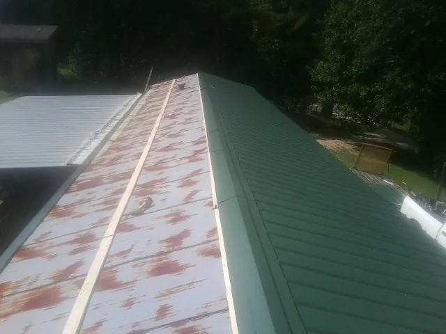 Old rusted panels beside newly installed green metal roofing — Wind Damage Roof Repair by Roofing Brothers in Ceres