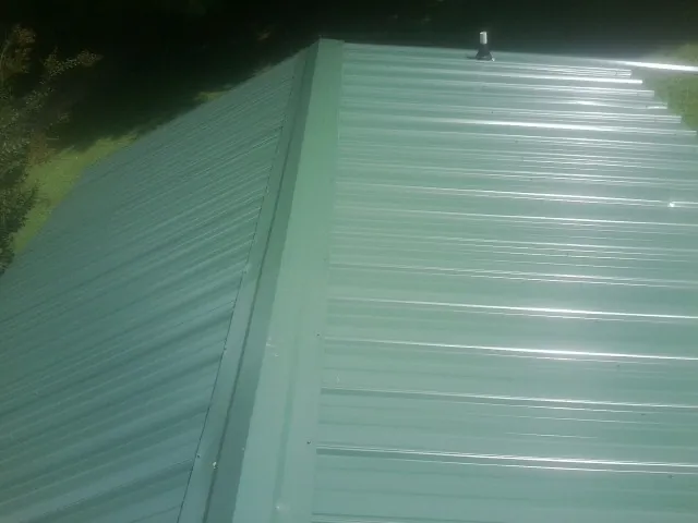 New green metal panels meeting at the ridge of a roof — Flat Roof Repair work by our crew in Ceres