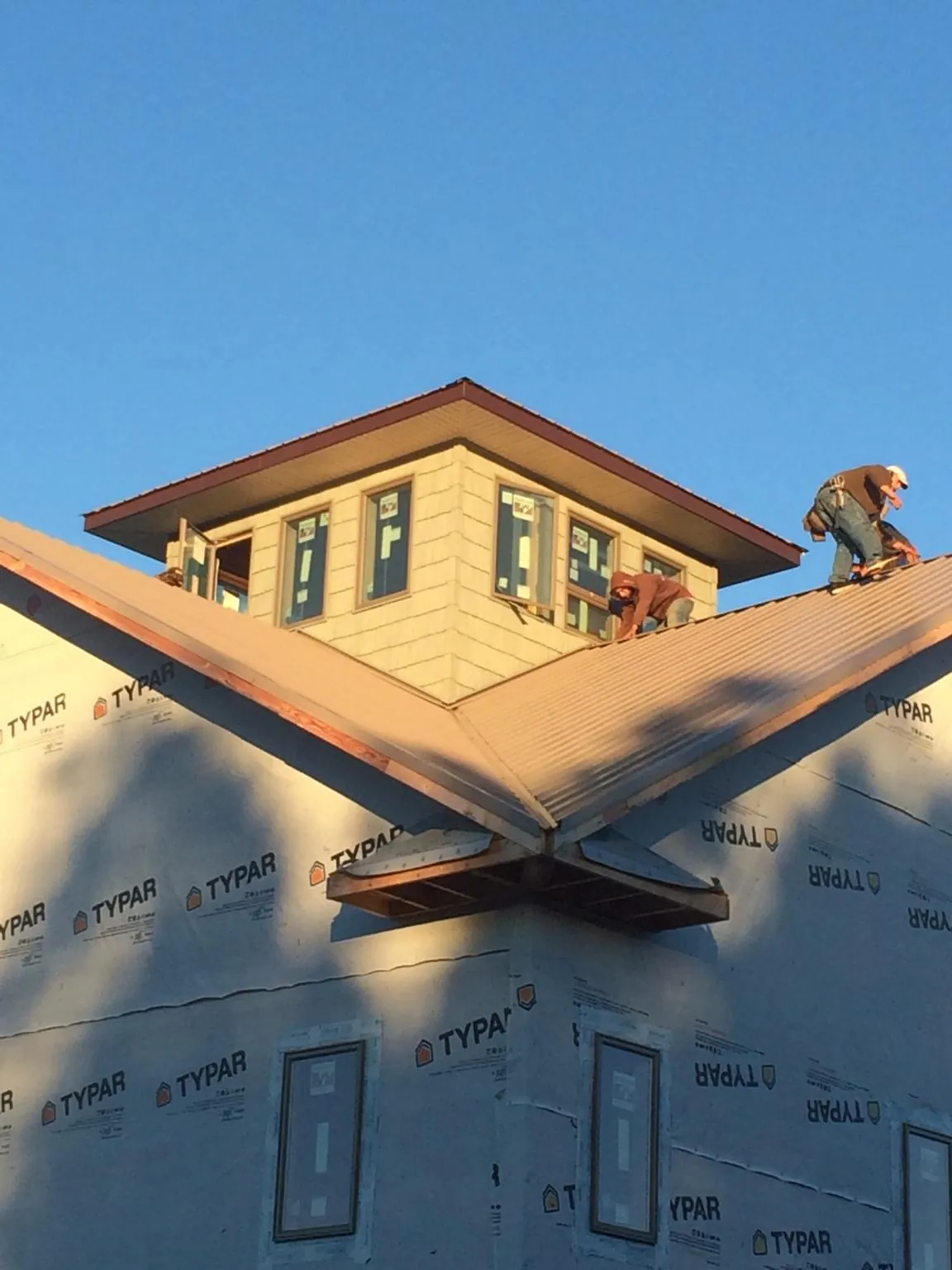 Roofers working around a rooftop cupola on a new metal roof at sunset — Roof Waterproofing in Ceres by Roofing Brothers